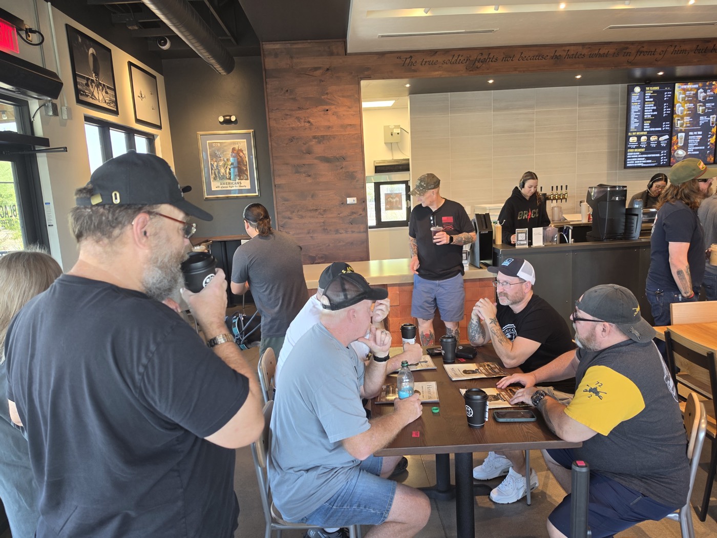 Veterans seated at tables with coffee, talking with each other inside Black Rifle Coffee in Tucson.